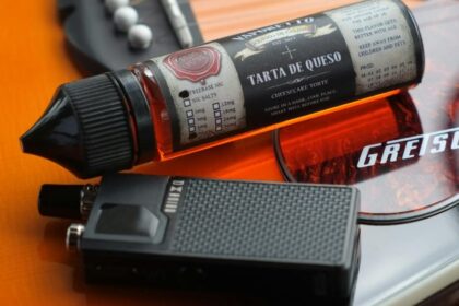 Vapretto Tarta de Queso cheesecake vape juice bottle and mod device resting on a Gretsch guitar body